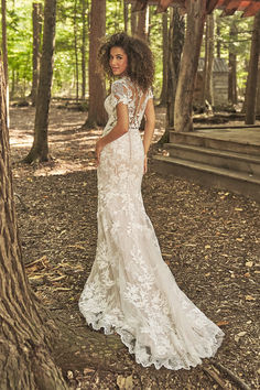 a woman standing in the woods wearing a wedding dress