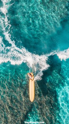 a man riding a surfboard on top of a wave in clear blue ocean water