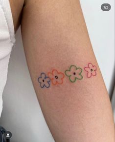 a woman's arm with colorful flowers on the left side of her arm and an arrow in the middle