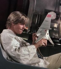 a man sitting in a chair holding a model airplane