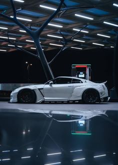 a white sports car parked in front of a building with its lights on at night