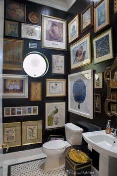 a black and white bathroom with lots of framed pictures on the wall above the toilet