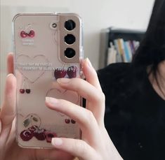 a woman holding up her phone case with cherries on it