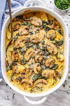 a casserole dish with mushrooms and spinach in it on a marble surface