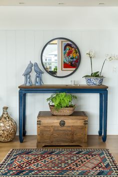 a room with a table, mirror and potted plants