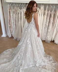 a woman is standing in front of some wedding gowns and looking at her dress