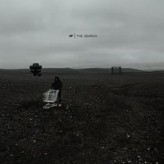 a person sitting on top of a shopping cart in the middle of a dirt field