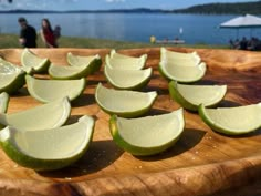 several pieces of lime sitting on top of a wooden cutting board with people in the background