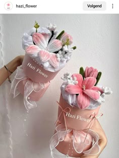 two vases with flowers are on display in front of a white wall, one is pink and the other is red