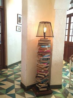 a lamp sitting on top of a stack of books next to a tall book case