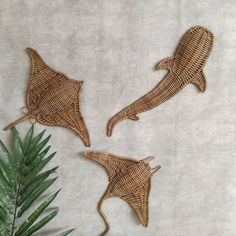 three woven wall hangings with plants in the background