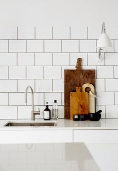 a kitchen with white tiles and wooden cutting board