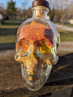 a glass bottle with a flower in it sitting on top of a wooden table next to a park