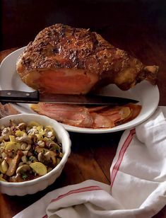 a plate with meat and vegetables on it next to a bowl of mushrooms, bread