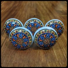 four decorative knobs on a wooden surface with blue and orange designs in the center