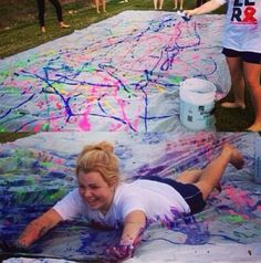 a woman laying on top of a blanket covered in colorful paint next to other people