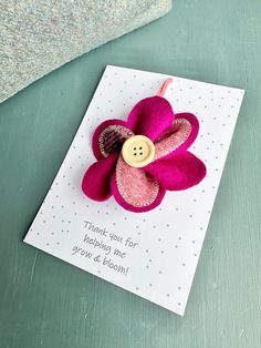 a card with a pink flower on it and a button attached to the back of it