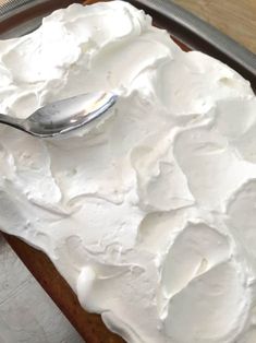 a close up of a cake on a pan with a spoon in it and frosting