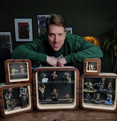 a man is posing for a photo with some figurines in front of him