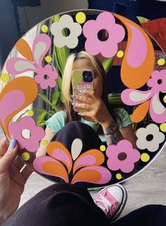 a woman taking a selfie with her cell phone in front of a flowered mirror