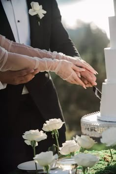 the bride and groom are cutting their wedding cake with white flowers in front of them