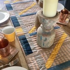 a table topped with plates and cups on top of a wooden table covered in plaid cloth