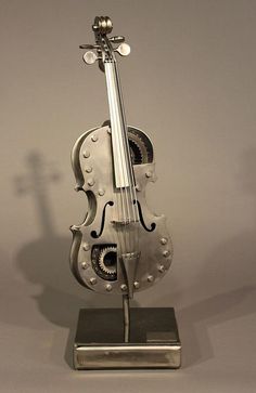 a silver violin sculpture sitting on top of a metal base