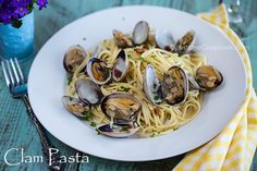 a plate of pasta with clams and parmesan cheese on a wooden table