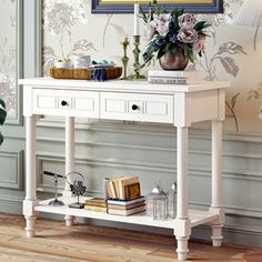 a white console table with flowers and books on it