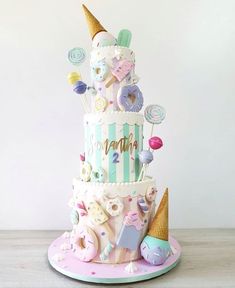 a three tiered cake with ice cream cones, candy and candies on top