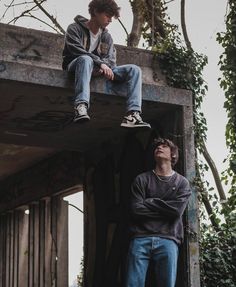 two young men sitting on top of a building