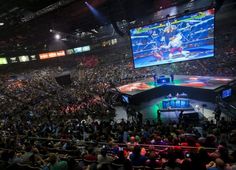 a large crowd is watching a video game being played on the big screen in an arena