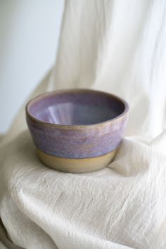 a purple bowl sitting on top of a white cloth