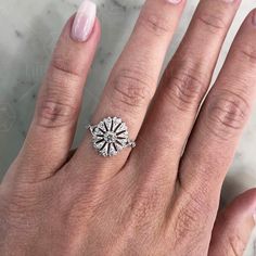 a woman's hand with a diamond ring on top of her finger and the other hand holding an engagement ring