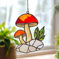 a stained glass lamp hanging from a chain next to a potted plant in front of a window