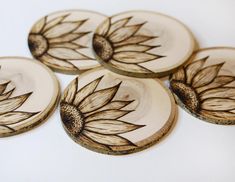 four wooden coasters with sunflower designs on them