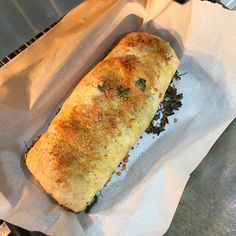 a long piece of bread sitting on top of a white paper bag next to a frying pan