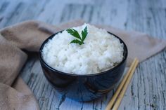 a bowl filled with rice next to chopsticks on top of a wooden table