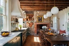 a kitchen with an old brick fireplace and wood flooring, surrounded by large windows