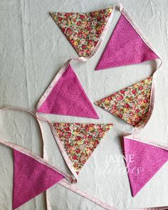 four triangle shaped buntings on top of a piece of paper with pink and green flowers