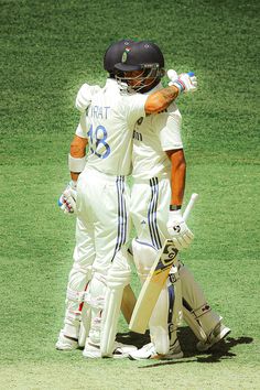 two cricket players hugging each other on the field