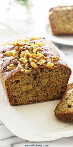 a loaf of banana nut bread on a white plate with two slices cut from it