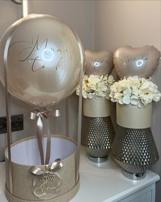 two vases with flowers and balloons on a table