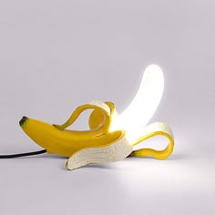 a banana shaped lamp sitting on top of a white table next to a black cord