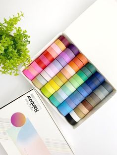 a box of washi tape next to a potted plant on a white table