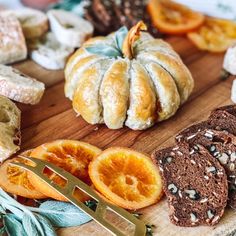 an assortment of breads and orange slices on a wooden cutting board with a knife