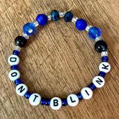 a blue and white beaded bracelet with words that spell out, do not blink