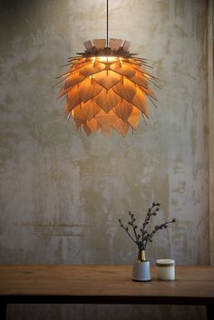 a light fixture hanging over a wooden table next to a vase with flowers in it