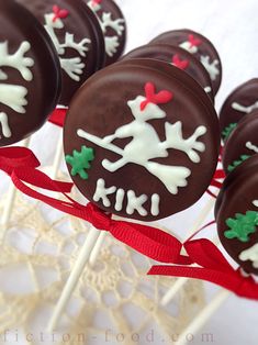 chocolate christmas cake pops with white frosting and red ribbons on a lace doily