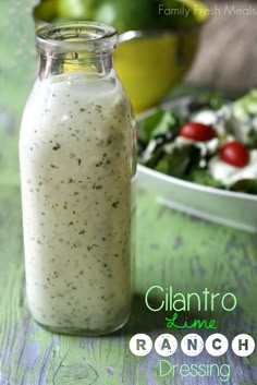 a glass bottle filled with dressing next to a salad